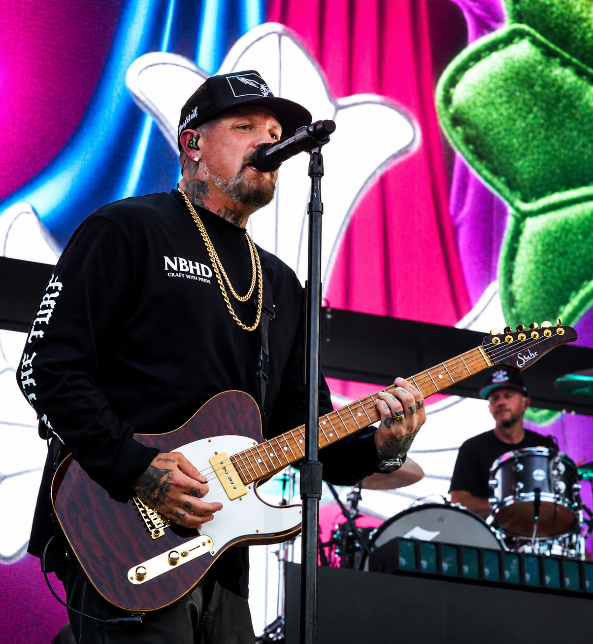Good Charlotte guitarist performing in front of a colorful stage