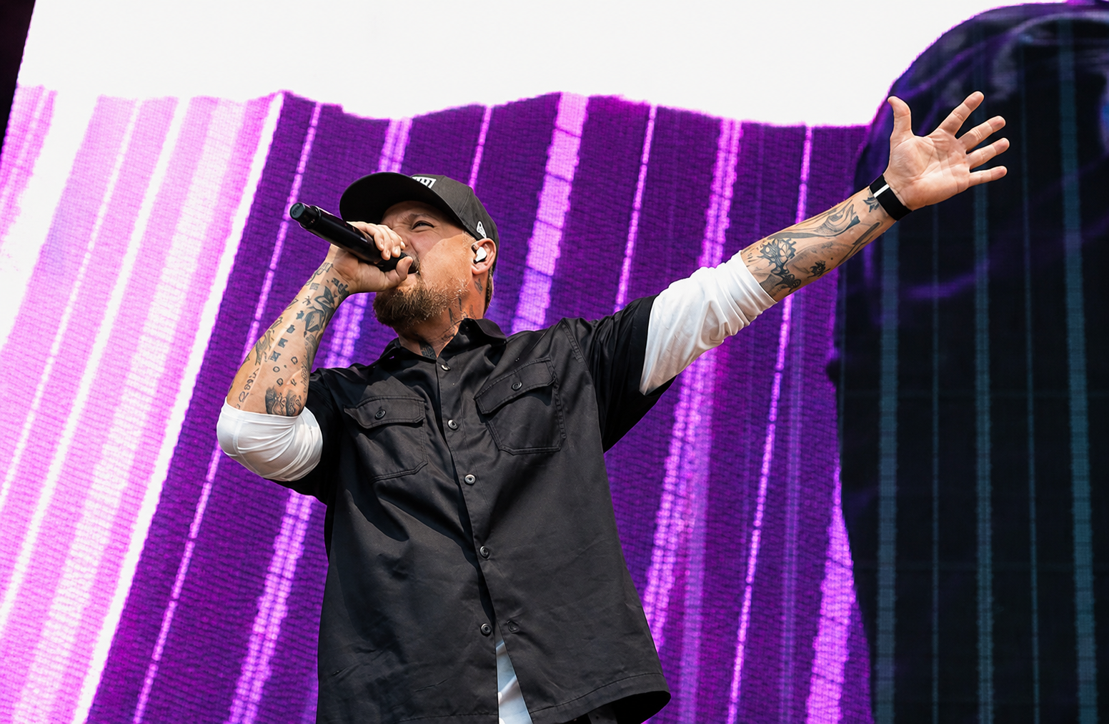 Good Charlotte singer reaching into the crowd from a purple-lit stage