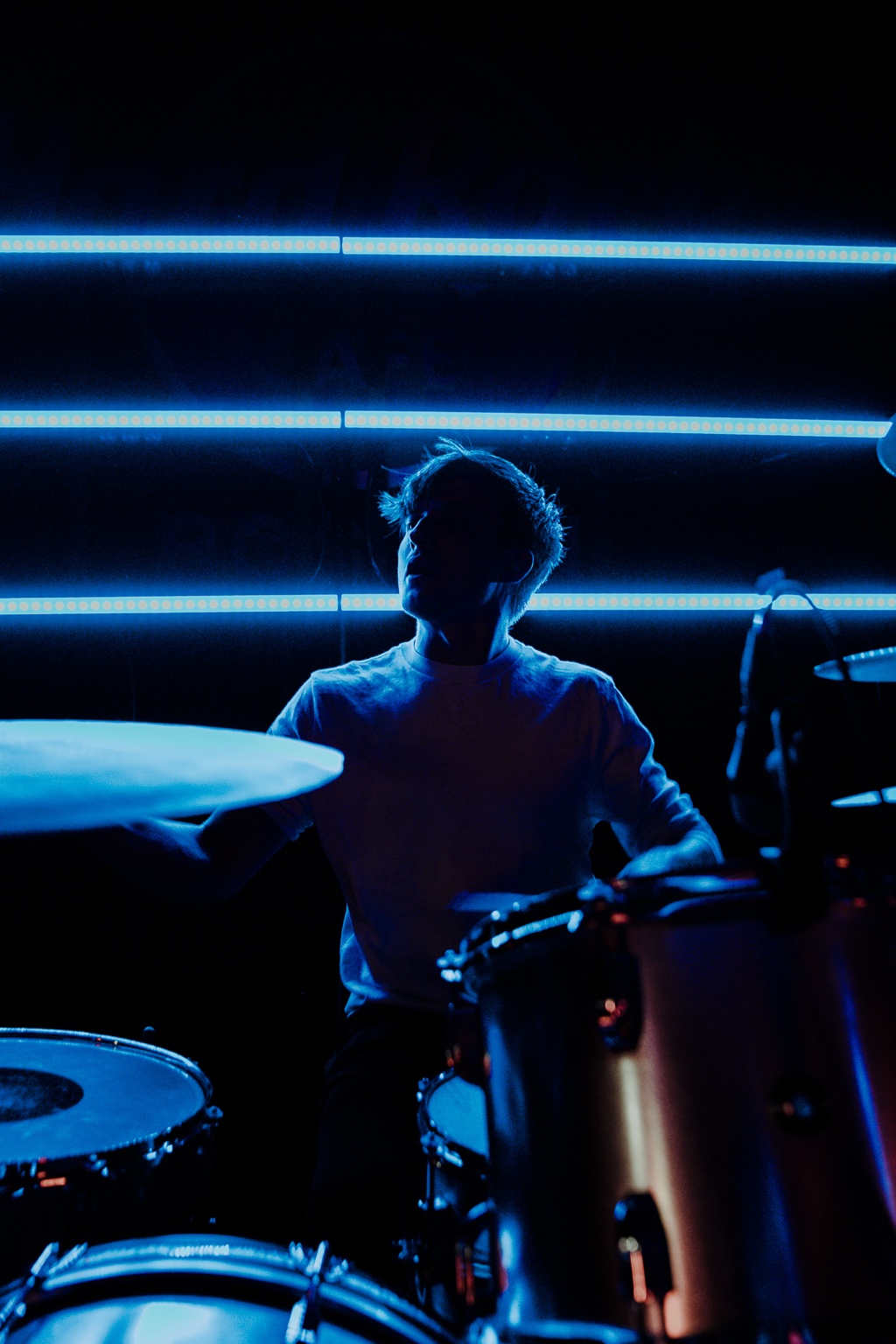 Vespera drummer performing beneath blue stage lights